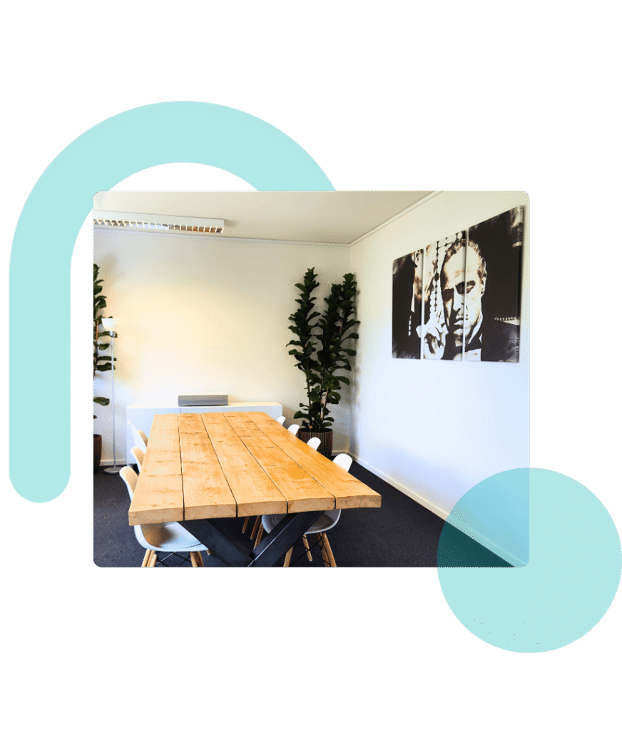 Montiertes Bild: Moderner Meetingraum in Leverkusen mit Holztisch, 8 Stühle, Beamer, Filmkunst an der rechten Wand, Pflanzen, Stehlampe, transparentes Logo-Wasserzeichen